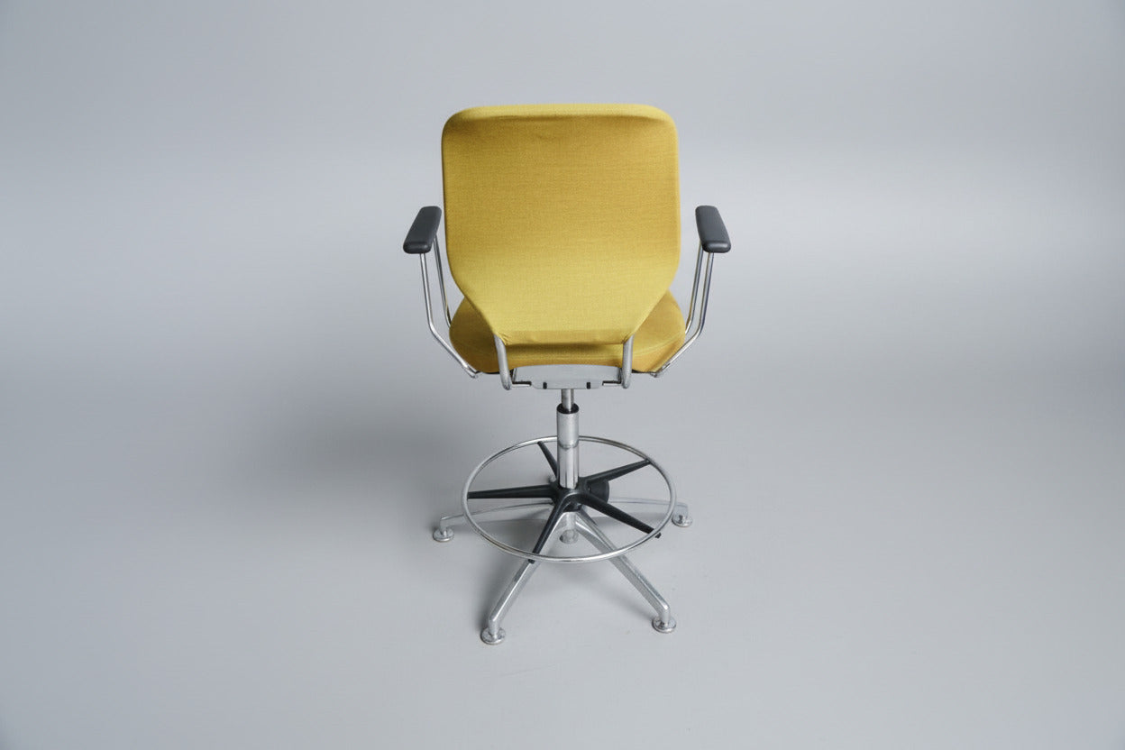 Savo kontorstol i gul polstring set bagfra med krom stel, fodstøtte og drejefunktion.