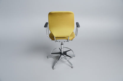 Savo kontorstol i gul polstring set bagfra med krom stel, fodstøtte og drejefunktion.