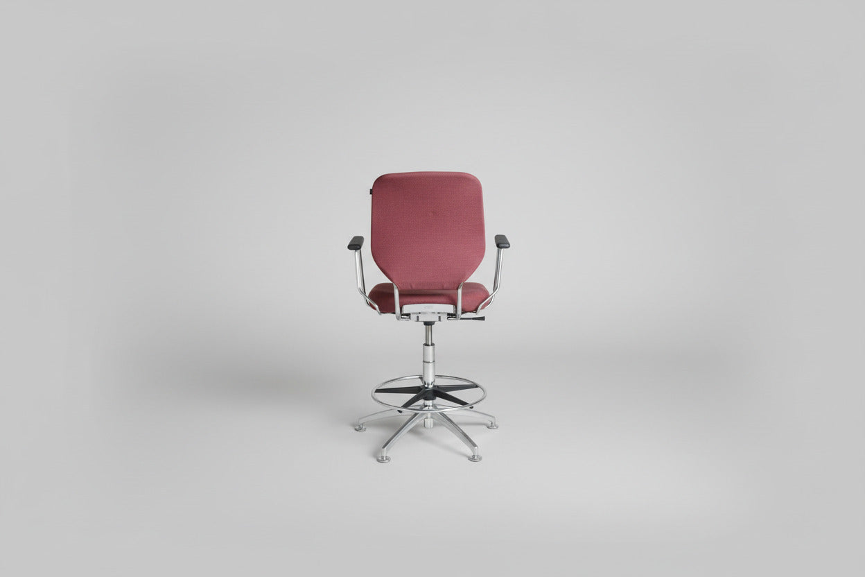 Savo kontorstol i rød polstring set bagfra med krom stel, fodstøtte og drejefunktion.