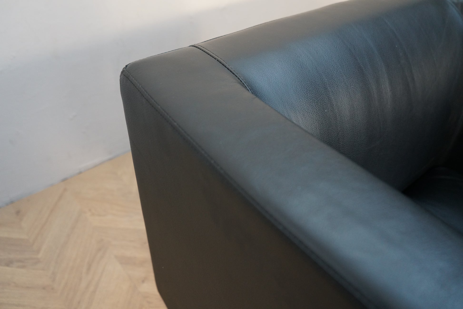 Close up af sort kunstlæder sofa med armlæn og metalben