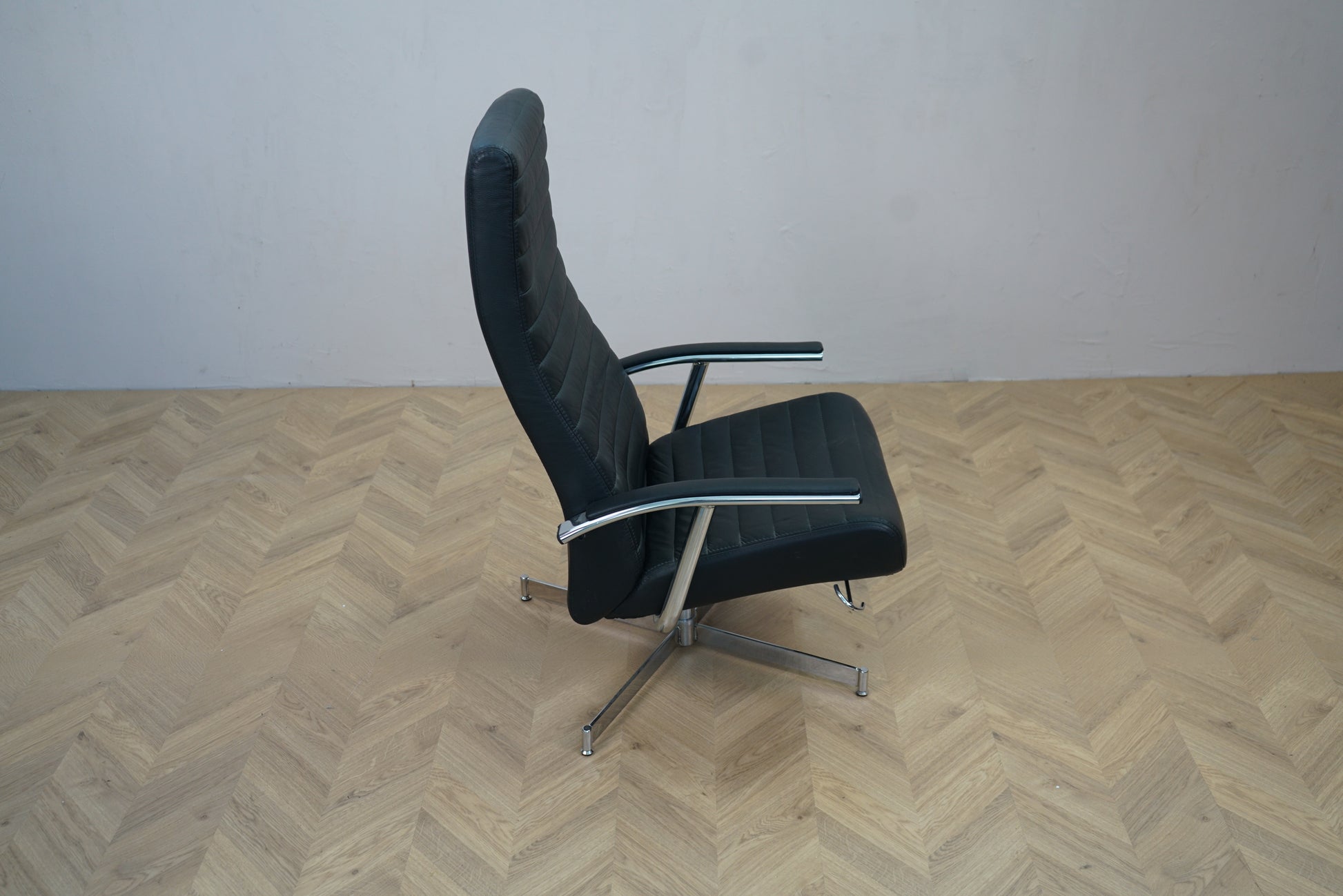 Elegant sort læder loungestol med vippefunktion og krom stel set fra siden