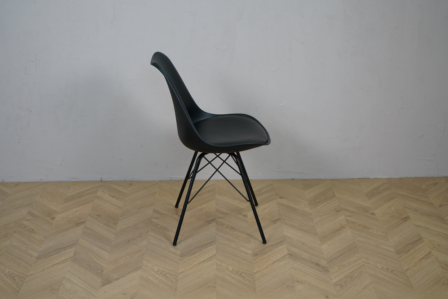 Sort caféstol set fra siden med sæde i sort kunstlæder