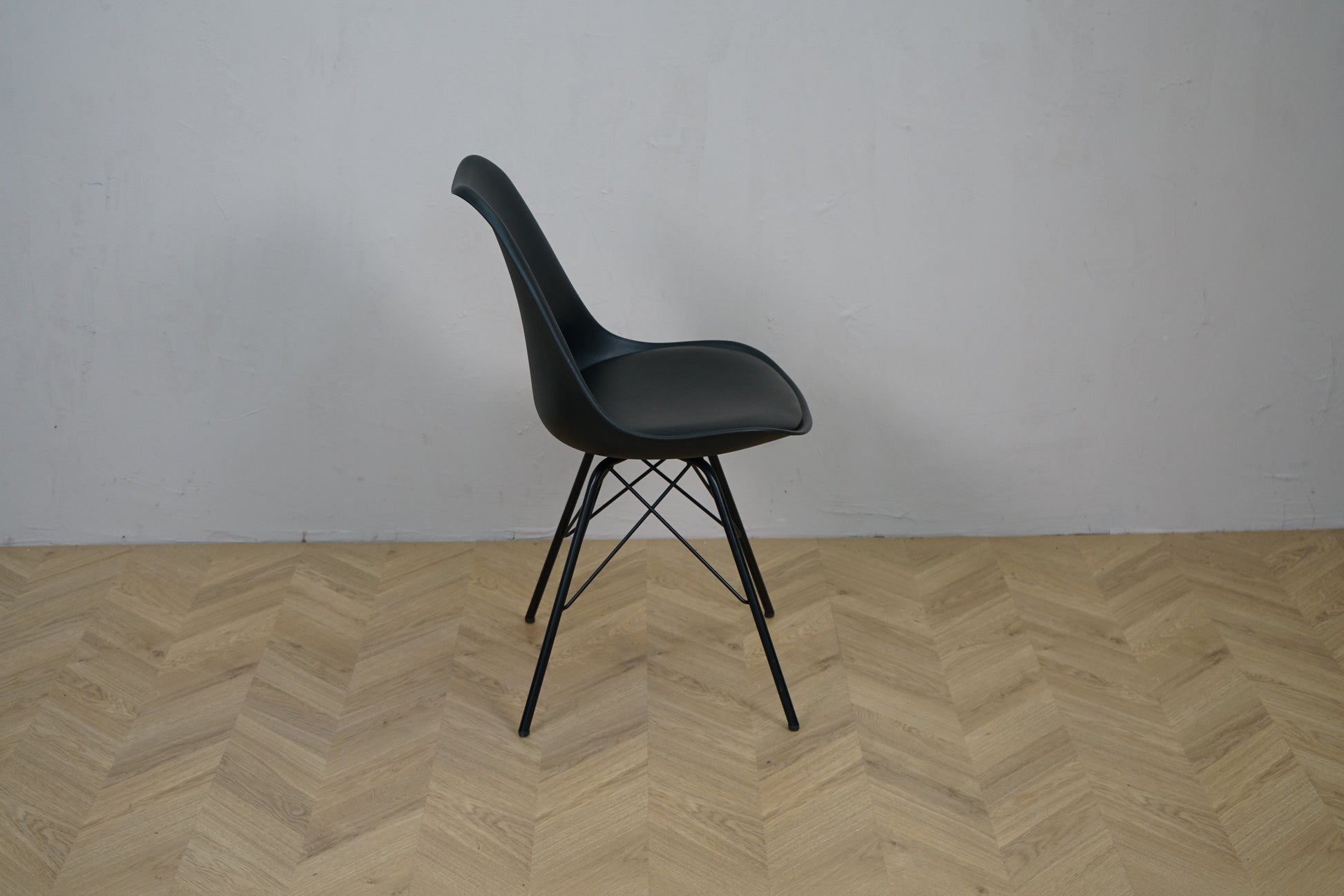 Sort caféstol set fra siden med sæde i sort kunstlæder