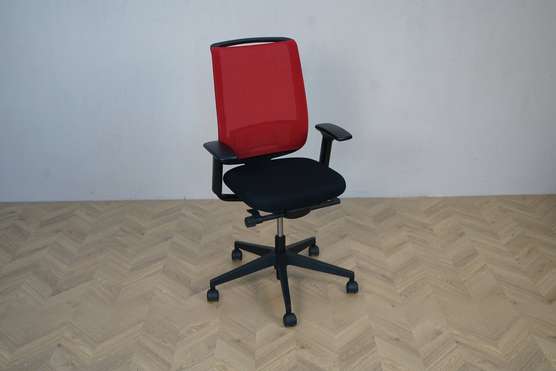 Steelcase kontorstol i skrå vinkel – moderne design med rød ryg og sort polstret sæde
