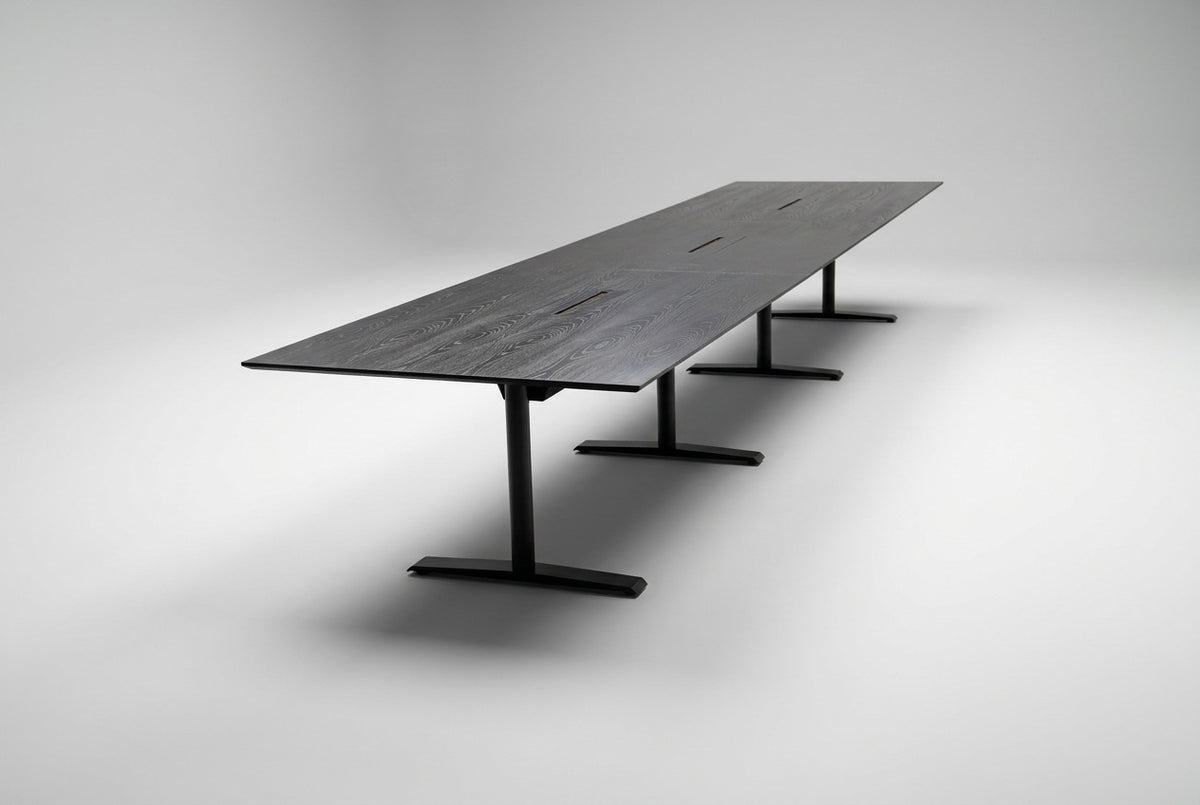 Stort konferencebord i sort eg med sort stel, affaset kant og kabelgennemføringer, 500x120 cm, set fra skrå vinkel.