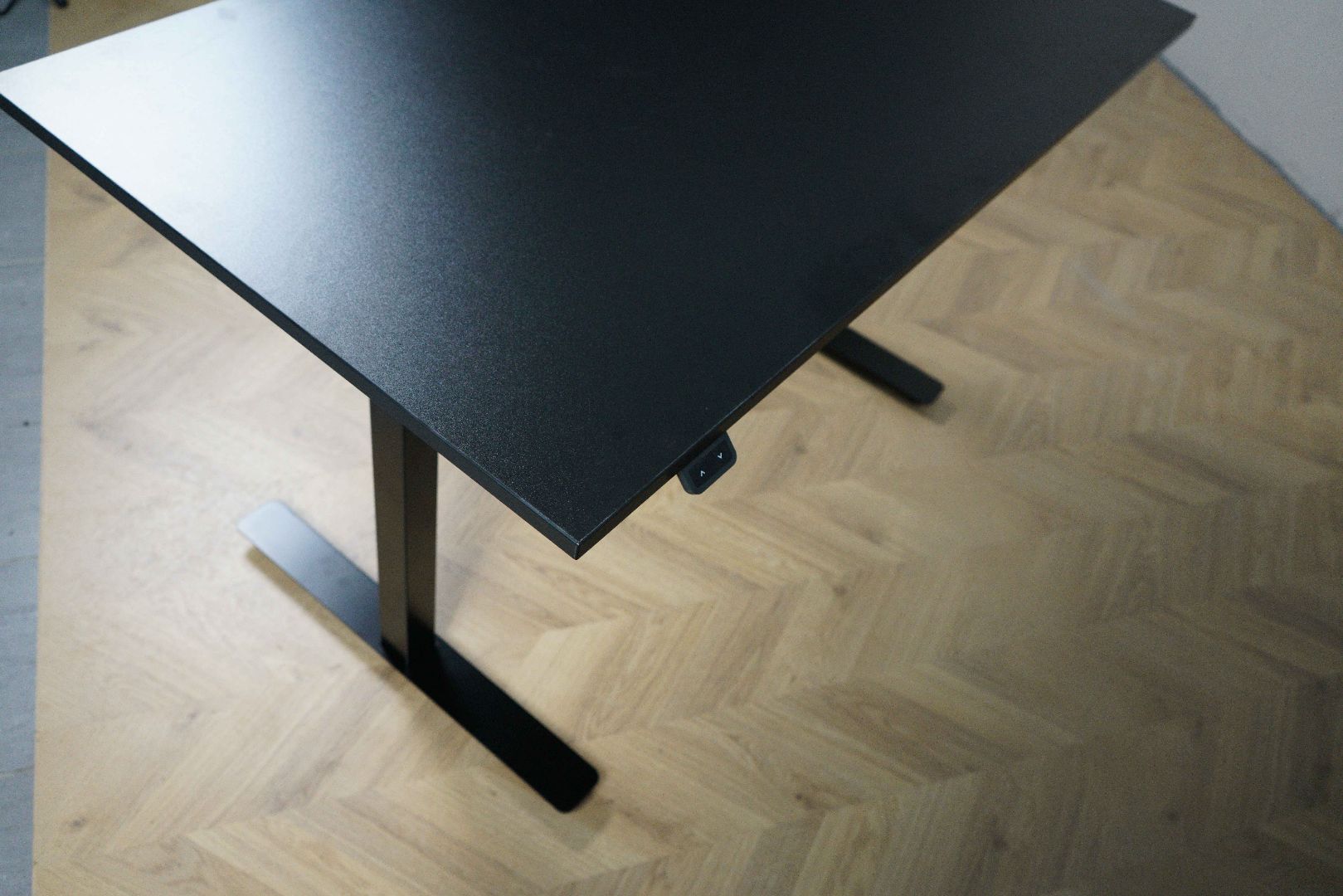 Nærbillede af hæve-sænkefunktion og bordkant på Sweds skrivebord 120x70 cm i sort