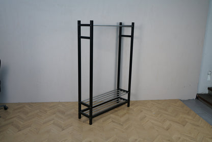 Sort tøjstativ i metal med hylde og bøjlestang set i skrå vinkel