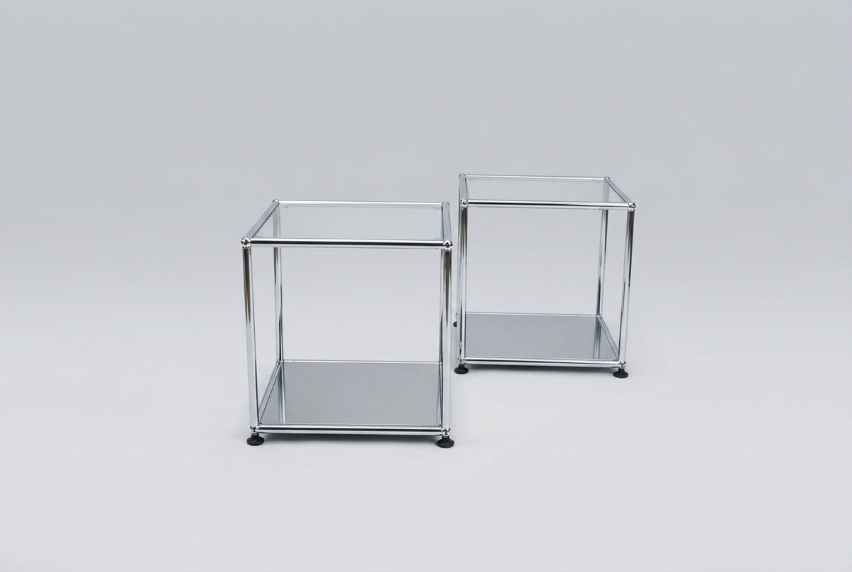 Sæt med 2 USM Haller sideborde i glas og krom med sort bundhylde, klassiske designerborde set fra skrå vinkel.