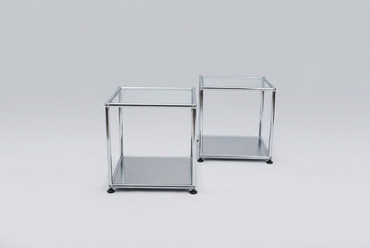 Sæt med 2 USM Haller sideborde i glas og krom med sort bundhylde, klassiske designerborde set fra skrå vinkel.