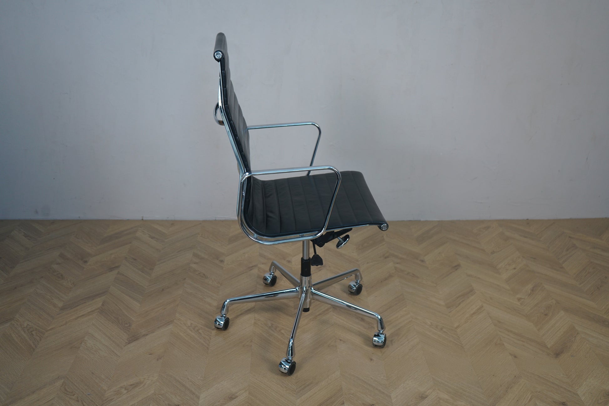 Vitra EA 119 kontorstol set fra skrå vinkel – sort læder, krom stel og klassisk Eames design