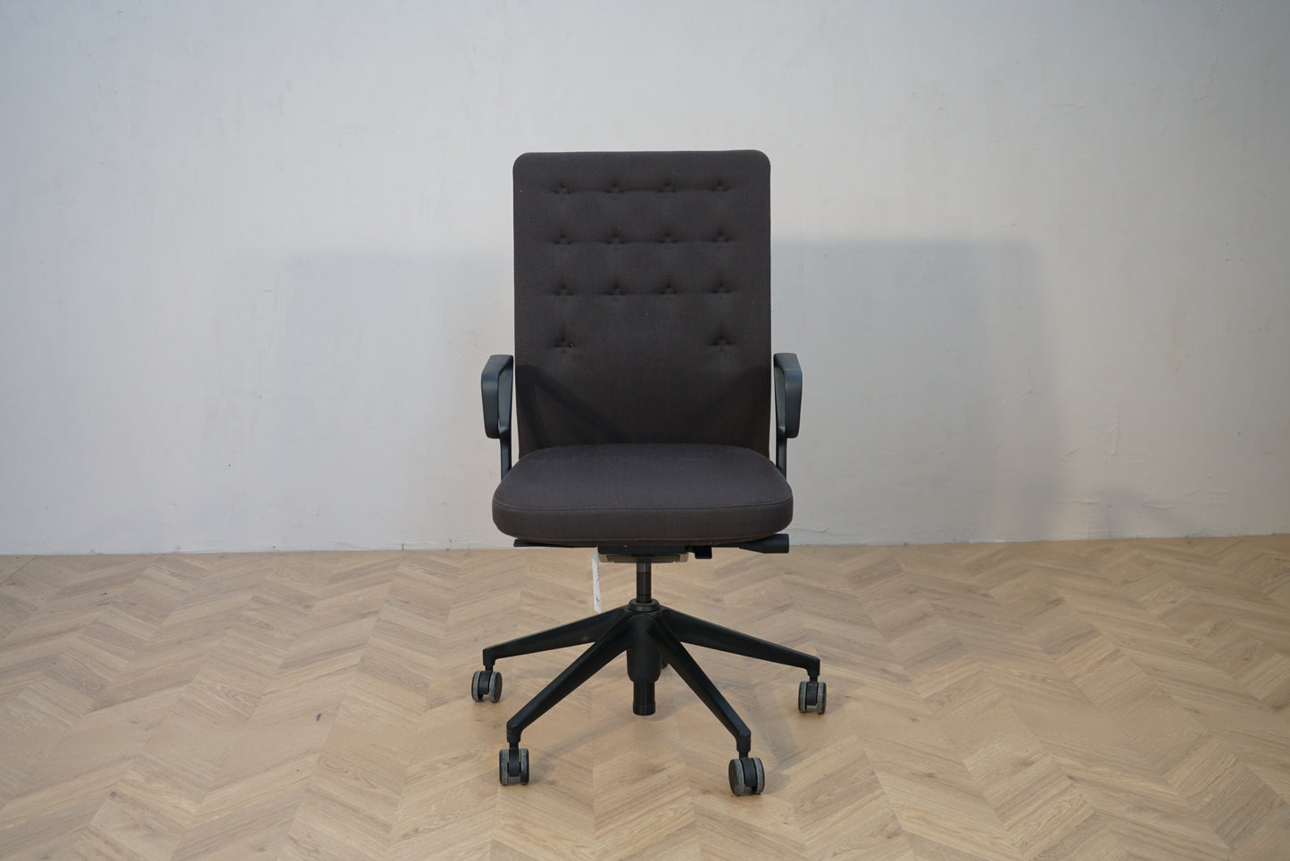 Vitra ID Trim kontorstol i mørkegrå polstring set forfra med sorte armlæn og sort fodkryds.