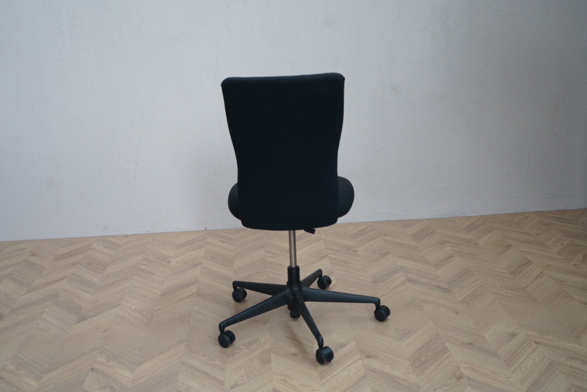 Bagfra visning af Vitra ID Trim kontorstol i sort uden armlæn med solid konstruktion og polstret ryglæn.